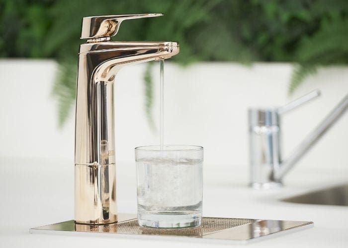 Billi XL Rose Gold dispenser on riser and font with glass of water