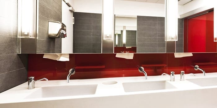 Chrome wall mounted sensor tap in commercial bathroom